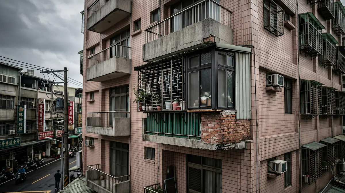 台灣住宅常見的陽台外推違建，沉重的建材加載於懸臂板邊緣，對建築結構造成潛在威脅。